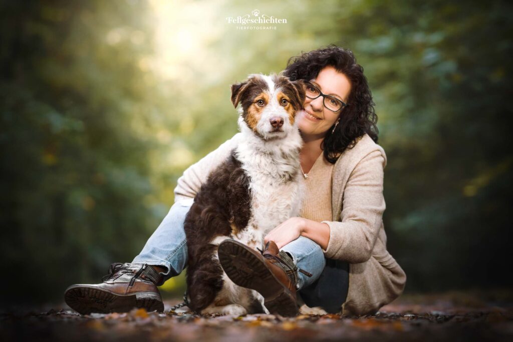 Hundefotografie von einer Frau mit ihrem Hund im Wald sitzend