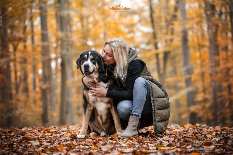 Frau hockt neben einem Großen Schweizer Sennenhund und küsst ihn