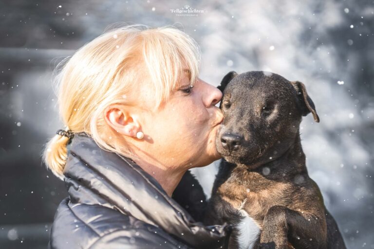 Hundefotografie von einem blinden Hund der einen Kuss von Frauchen bekommt