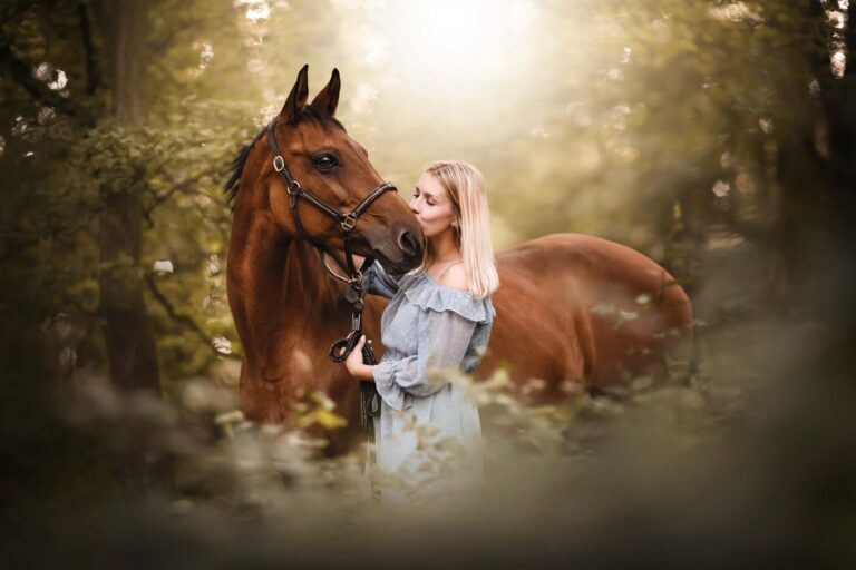 Frau küsst ihr Pferd im Wald