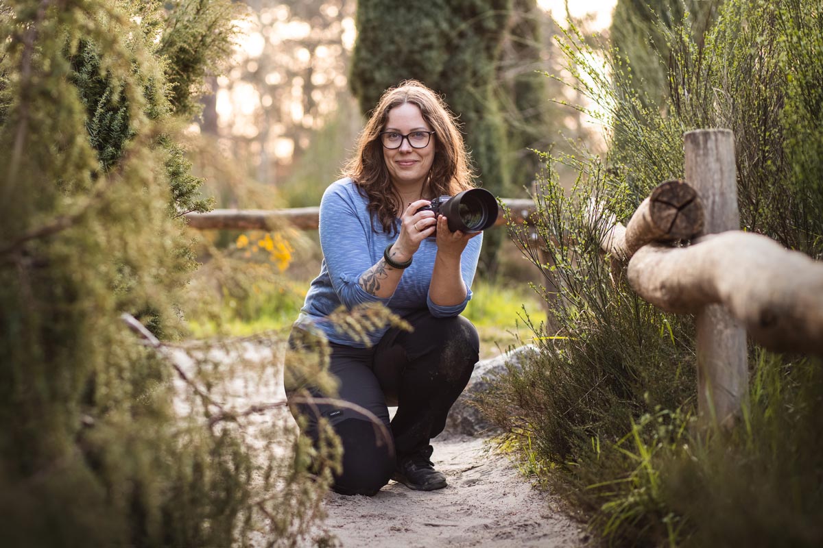 Fotografin Mandy Hoffmann hockt mit Kamera auf dem Boden