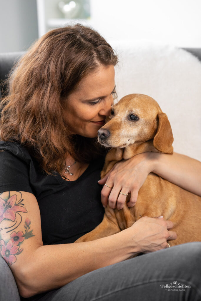Frau sitzt mit Hund in einem Sessel