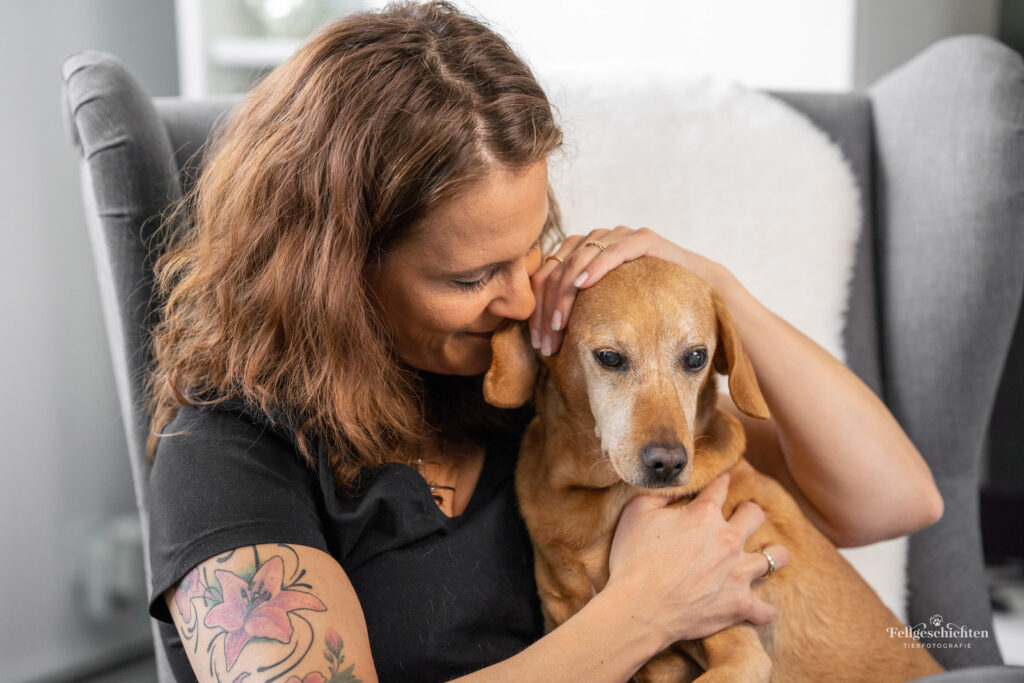 Frau sitzt mit Hund in einem Sessel