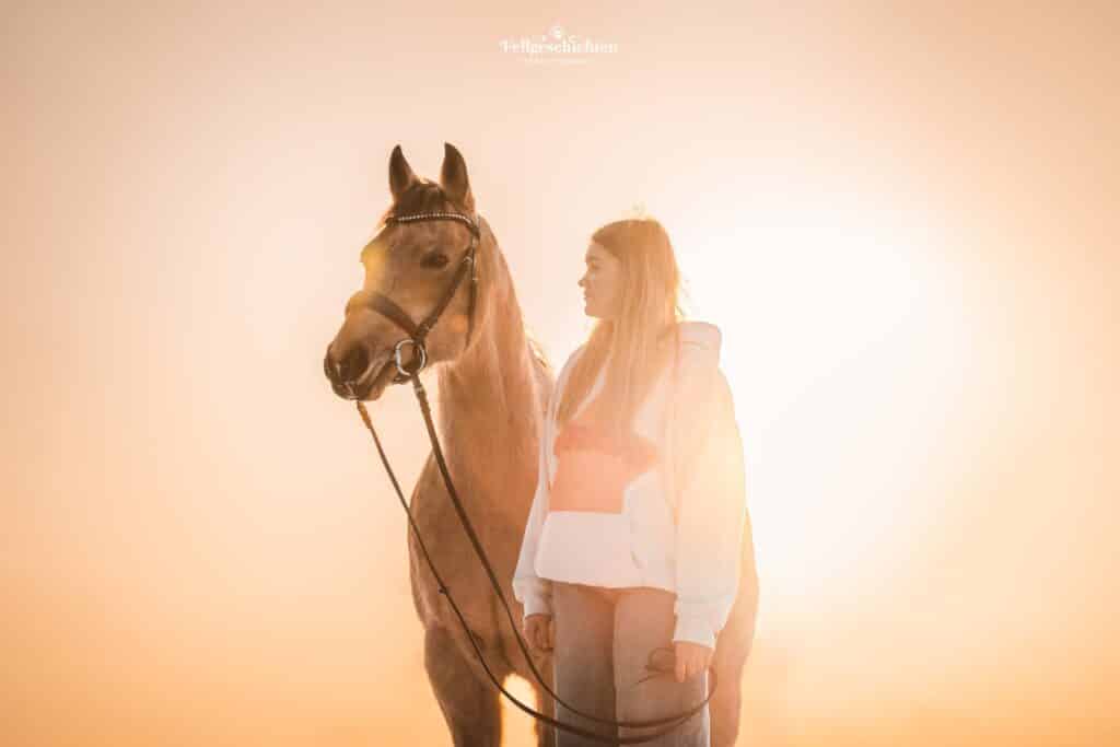 Mädchen mit ihrem Pferd im Sonnenuntergang