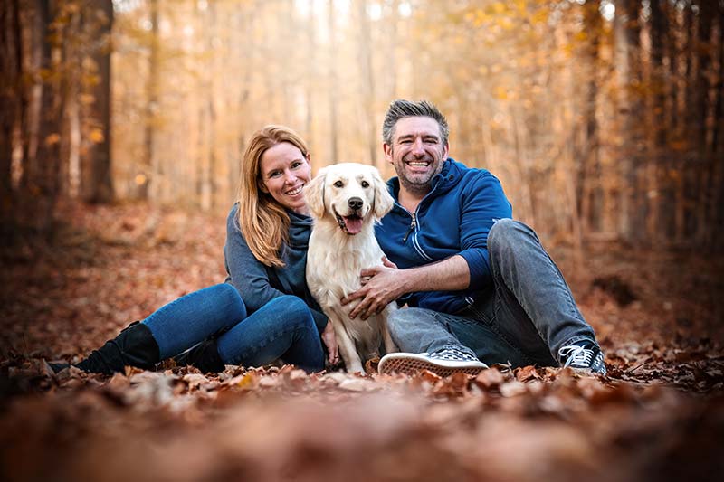 Paar sitzt mit Golden Retriever im Herbstwald. Beispiel Bildbearbeitung fertiges Bild