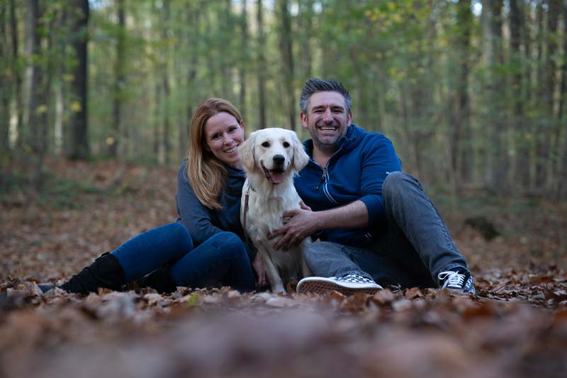 Paar sitzt mit Golden Retriever im Herbstwald. Beispiel RAW Bild ohne Bearbeitung