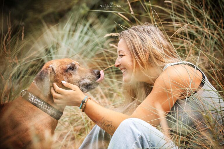 Frau kuschelt mit ihrem Rhodesian Ridgeback in den Dünen